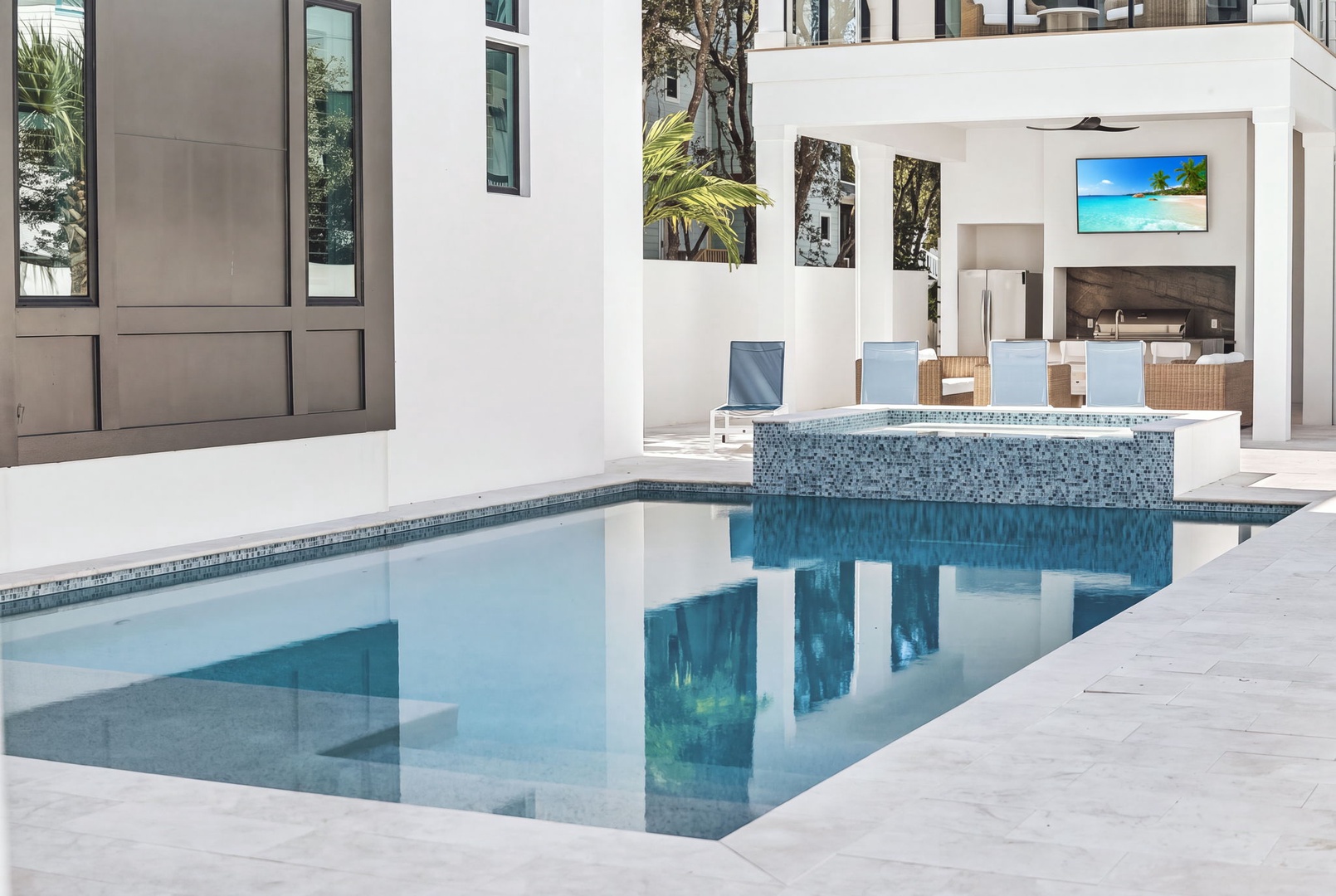 Dive into your private oasis with this stunning pool featuring a modern hot tub, all just steps from your stylish open kitchen and dining area.