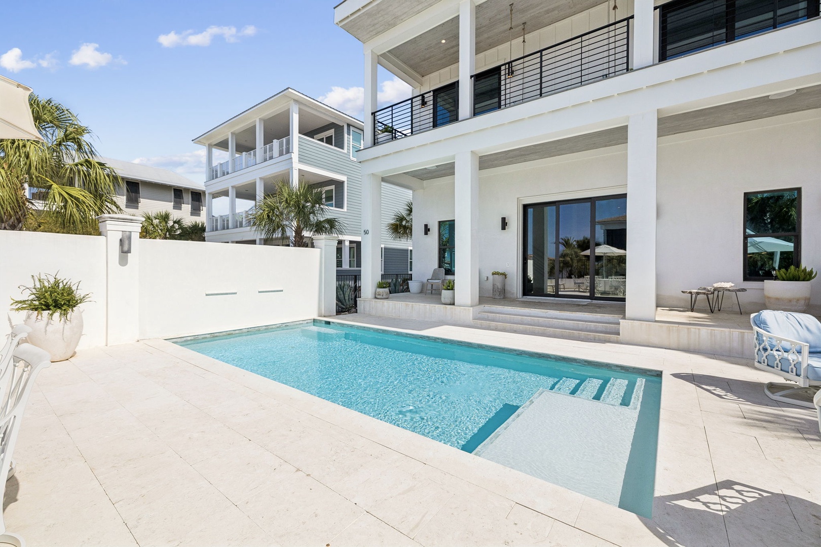 Modern vacation home featuring a pristine private pool surrounded by sleek architecture and tropical landscaping under sunny skies.