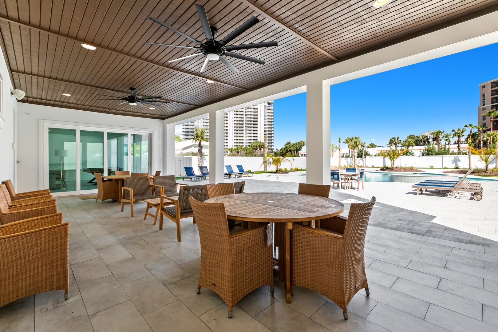 Your covered outdoor oasis awaits—relax under soaring wood-paneled ceilings with ceiling fans, dine at the round table, or unwind on the comfortable seating as you gaze out at the sparkling pool and sunny Florida day.