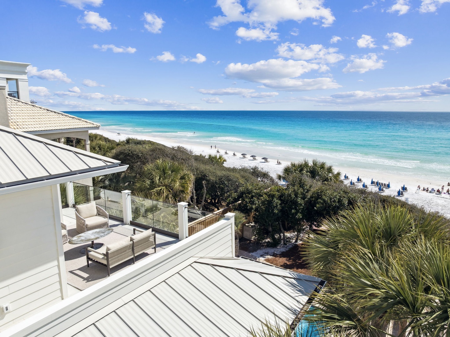 Stunning beachfront property with expansive deck overlooking pristine white sand beach and turquoise waters.