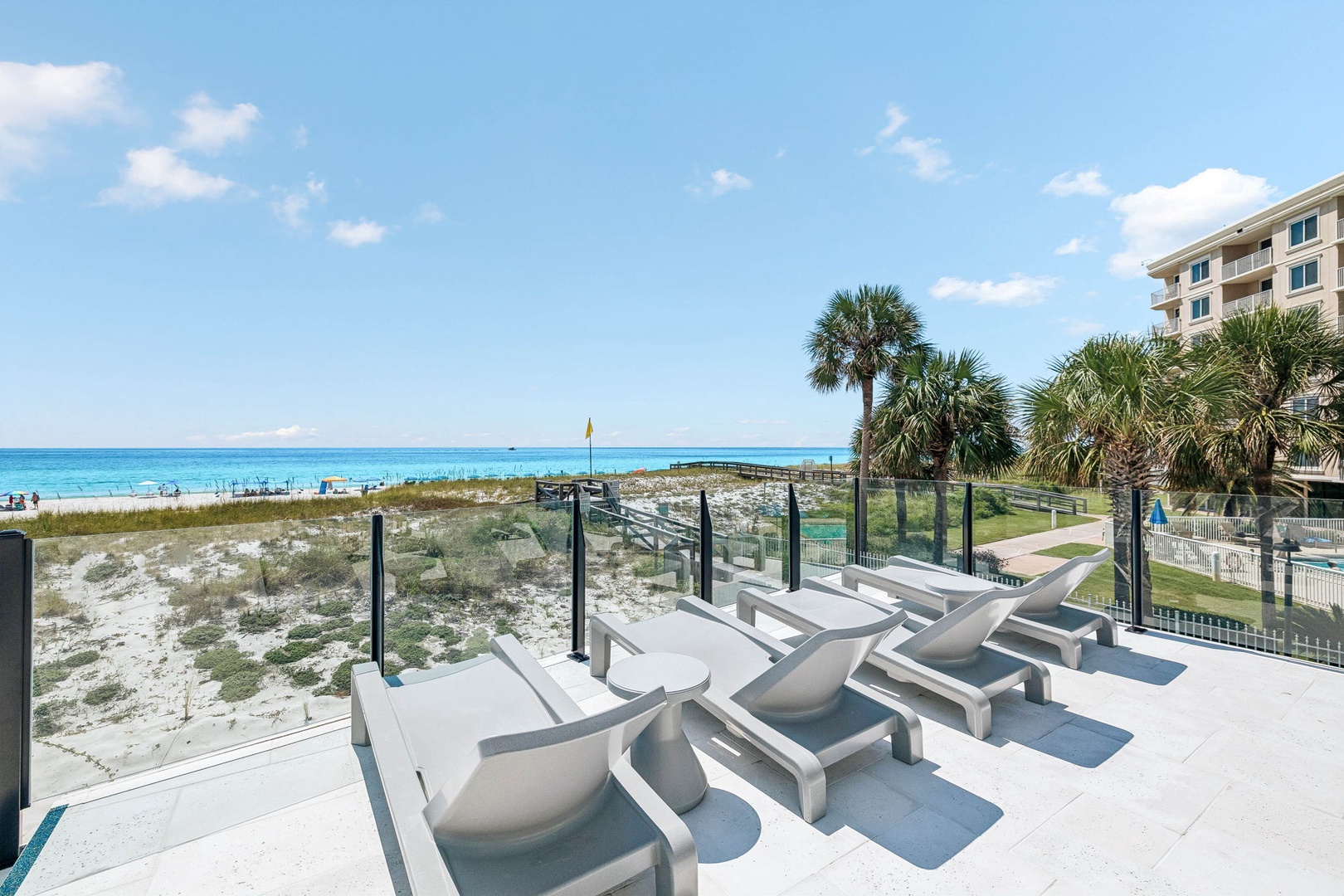Picture yourself unwinding on sleek sun loungers with the pristine beach and sparkling turquoise waters just steps away—your perfect coastal escape awaits.