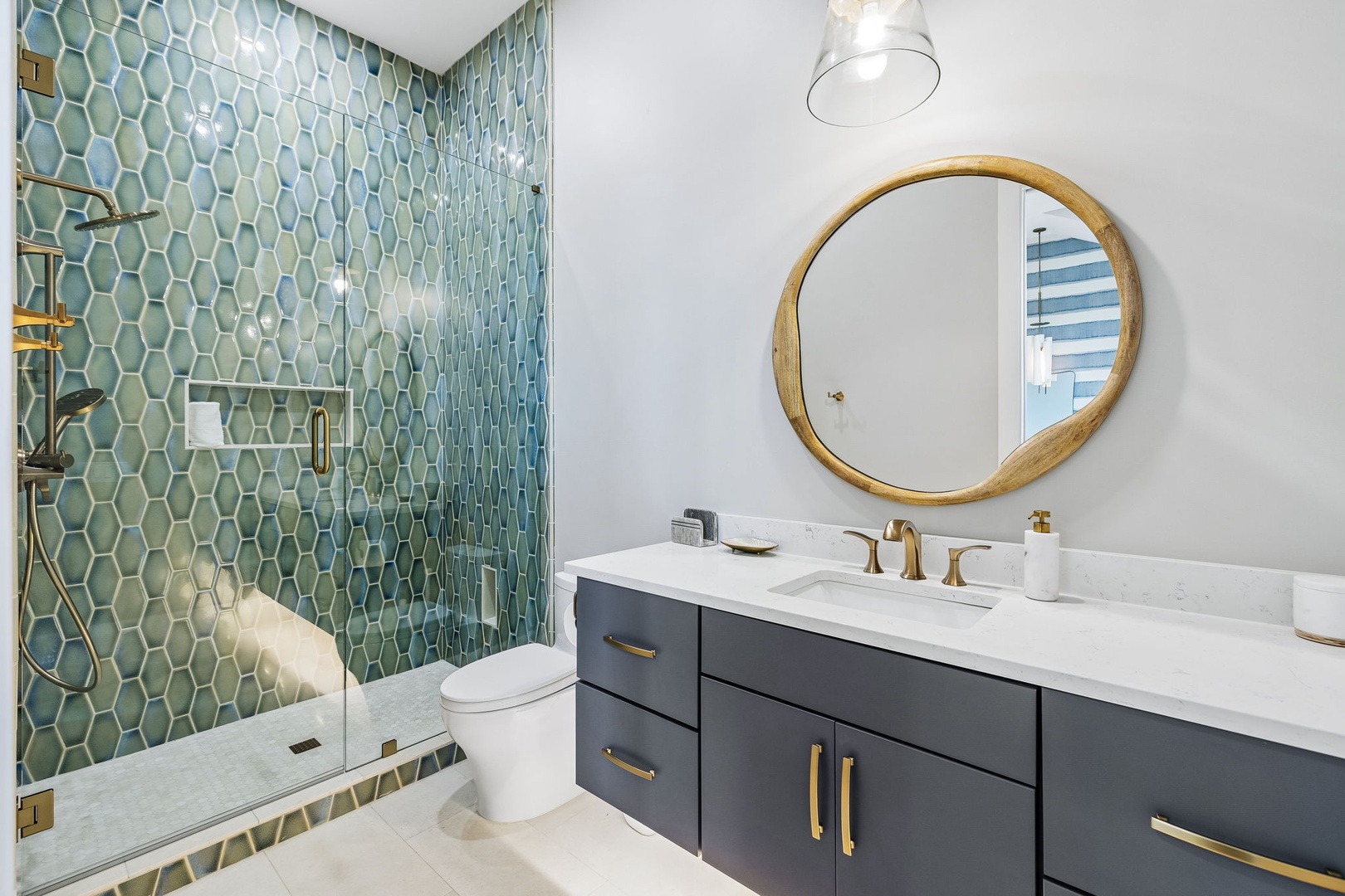 Your spa-like bathroom features stunning teal hexagon tile, gleaming brass fixtures, and a custom vanity that turns getting ready into a moment of luxury.