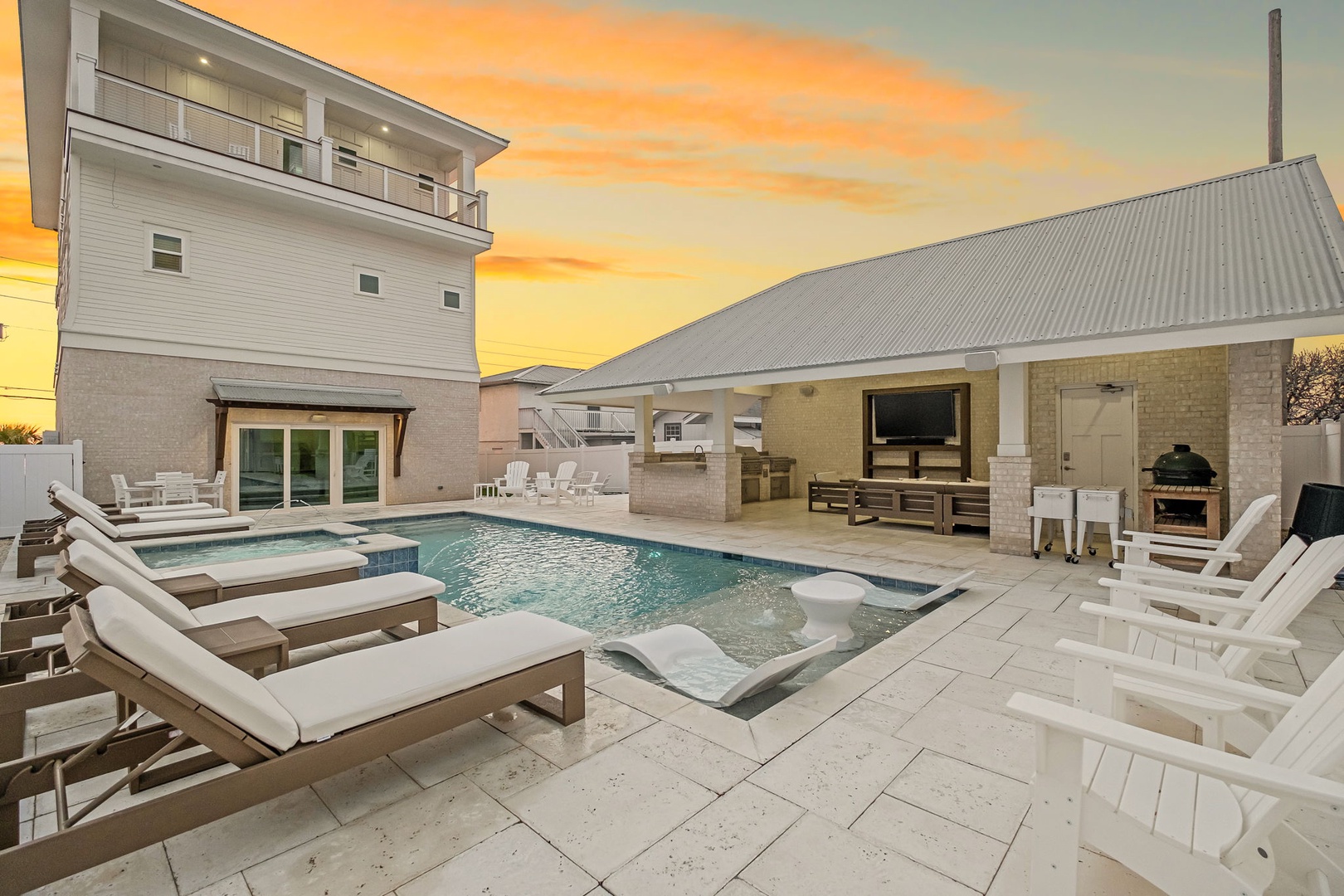 Stunning sunset views frame this luxurious backyard oasis with sparkling pool, outdoor kitchen, and elegant lounge seating.