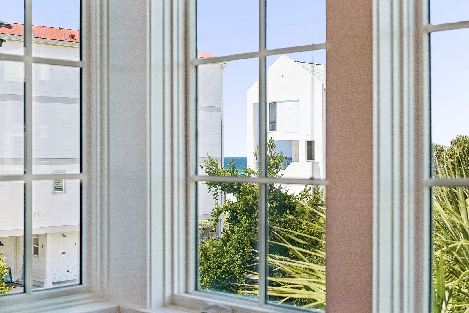 Residential properties and coastal greenery frame this view from the accommodation, featuring nearby houses and natural surroundings of the area.