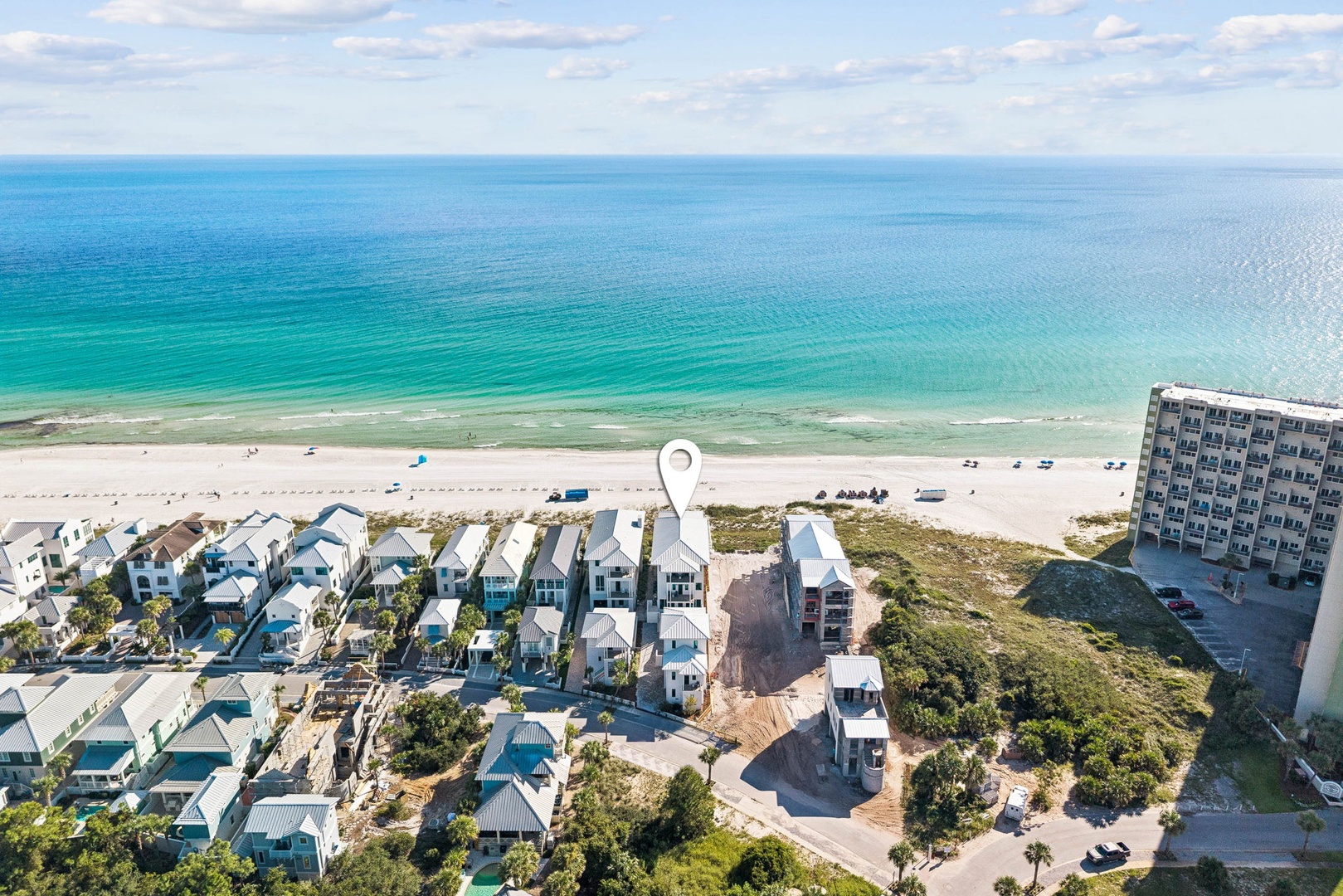 Aerial view showcasing the beachfront property location along pristine white sands and emerald Gulf waters, surrounded by coastal homes and natural dunes.