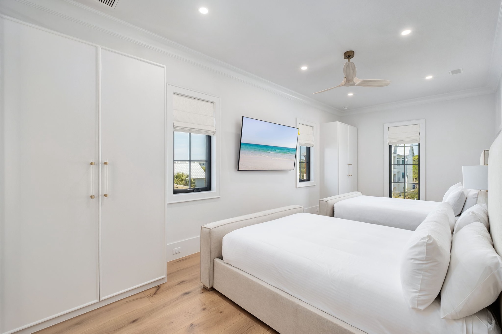 Drift off to sleep in this serene bedroom featuring twin beds with crisp linens and calming coastal artwork above.