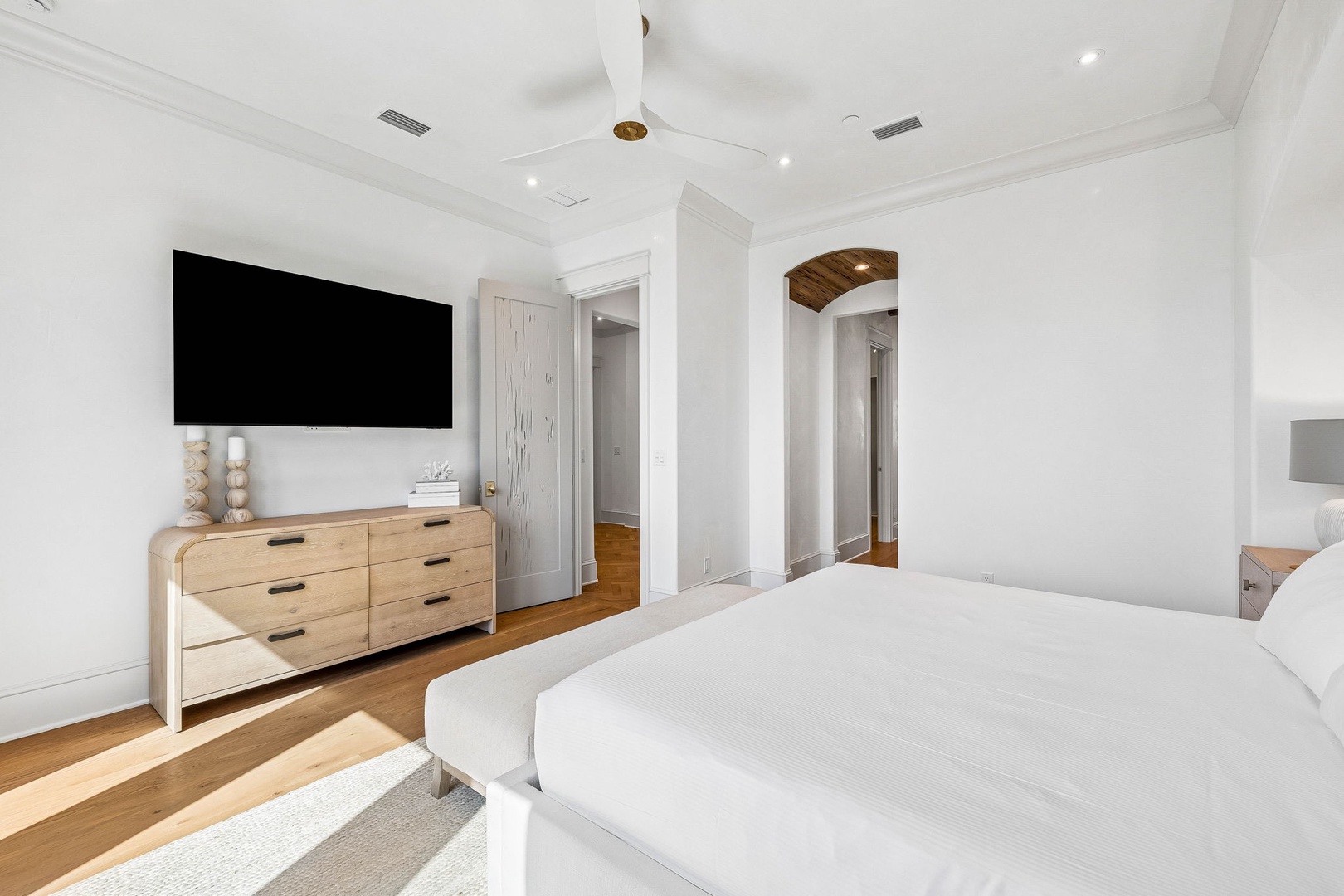 Sink into your plush bed with crisp white linens, enjoying modern comforts like the wall-mounted flat-screen TV. Warm wood floors and a sleek dresser complete your peaceful retreat.