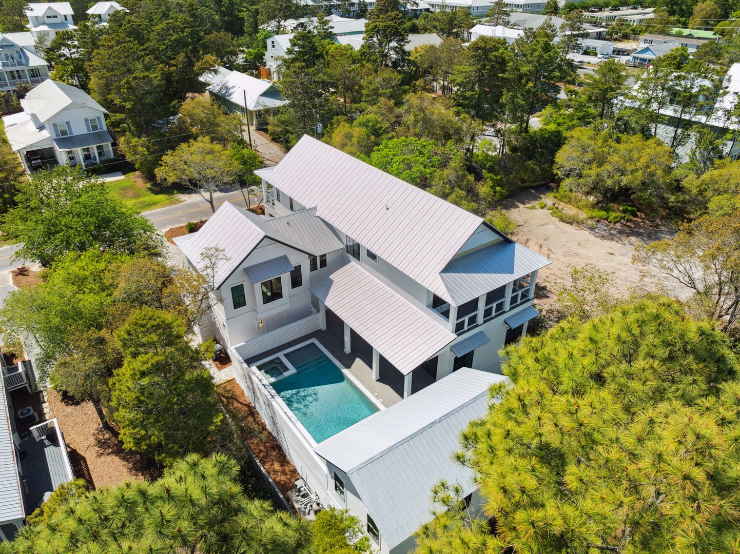 Modern coastal home with private pool nestled among mature trees in a peaceful residential neighborhood.
