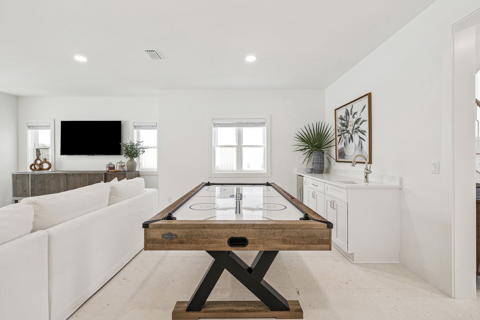 Your stylish game room features air hockey for friendly competitions, with comfy seating and a TV for relaxing between matches.