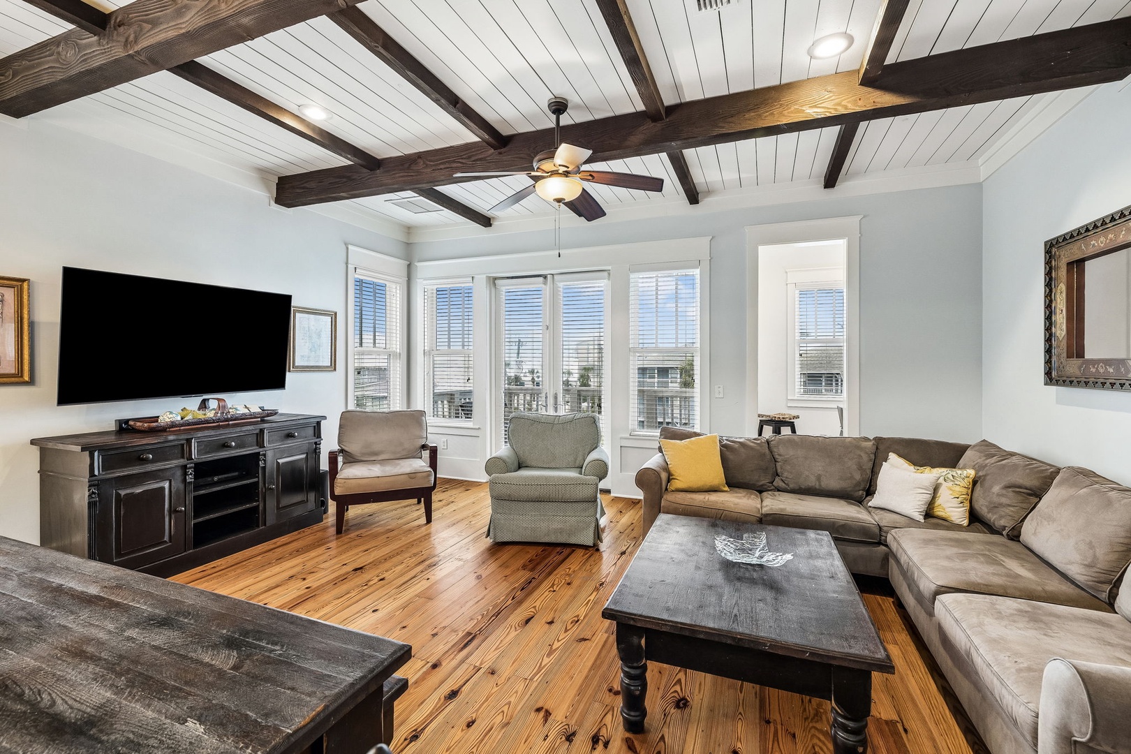 Relax under the striking vaulted ceiling with exposed beams as natural light streams through tall windows. Sink into the plush sectional and enjoy your favorite shows or unwind with a good book in this inviting living space.