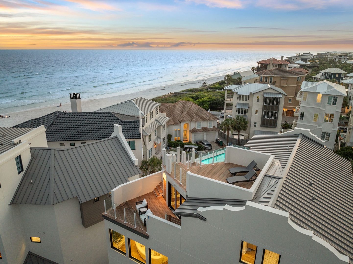 Aerial view capturing a luxury beachfront community at sunset, showcasing upscale coastal homes, private pools, and pristine sandy shores along the Gulf Coast.