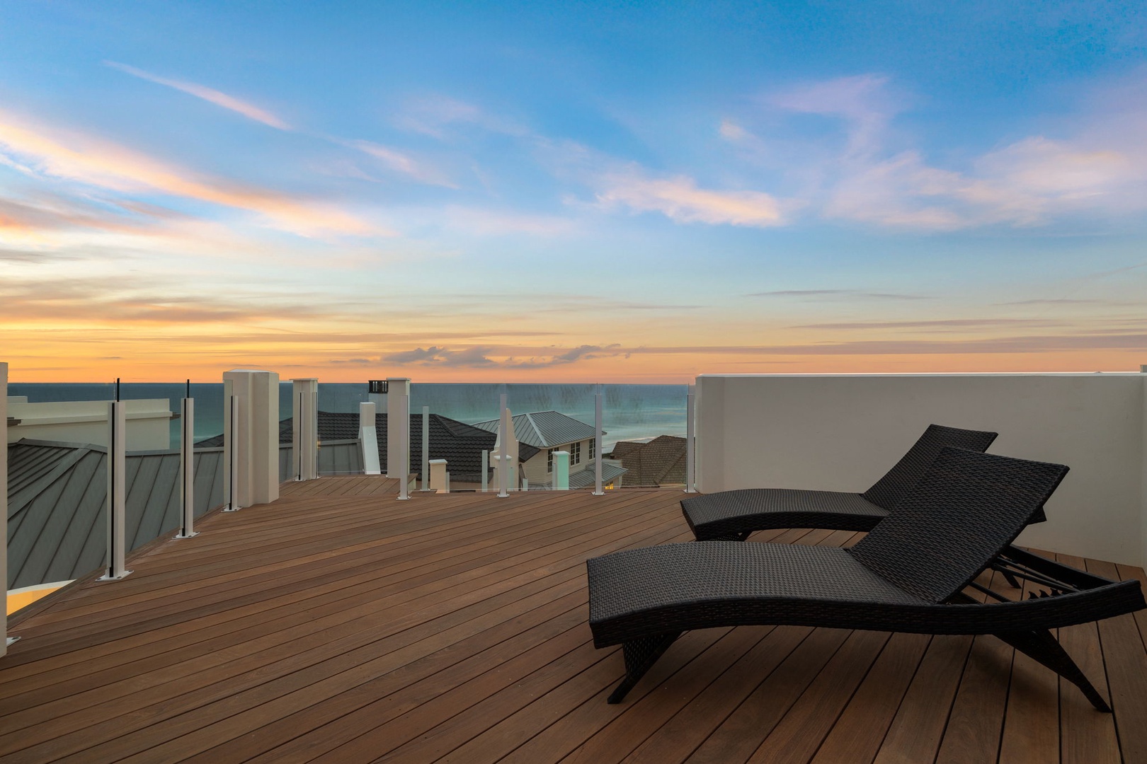 A rooftop terrace offers panoramic views of the coast and neighbourhood, featuring sleek modern loungers on warm timber decking—an ideal spot for tranquil evenings.
