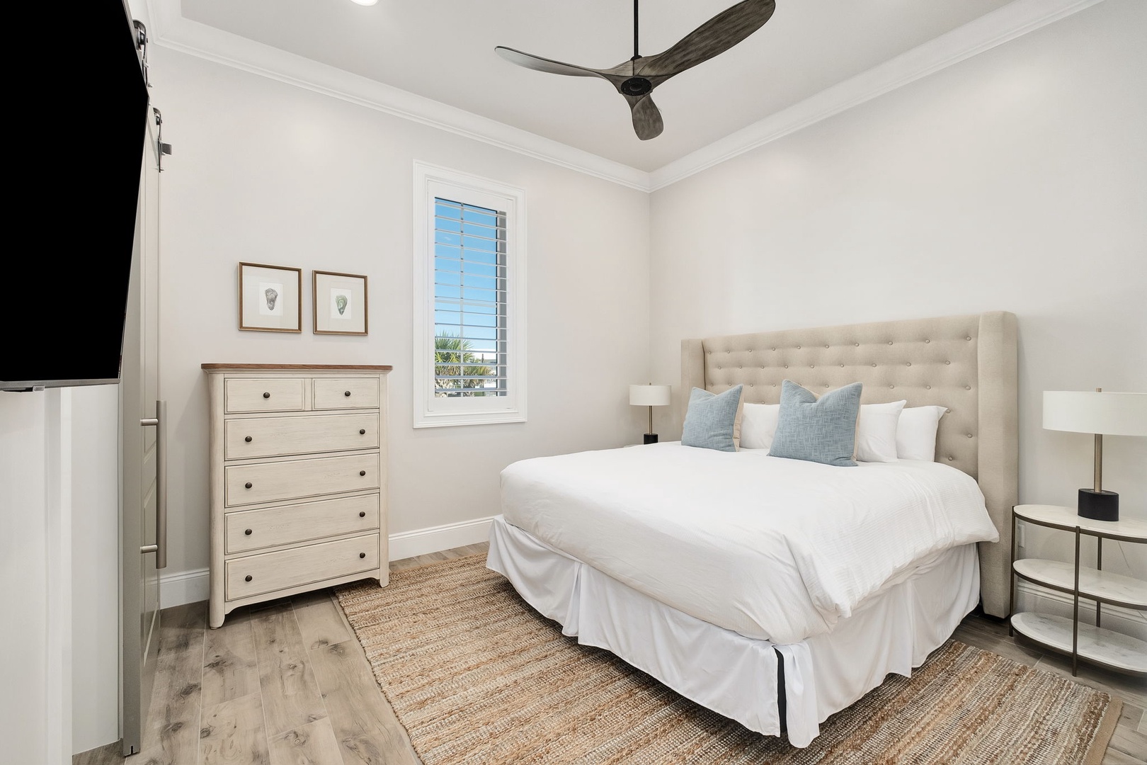 Sink into crisp linens and coastal comfort in your serene bedroom retreat, complete with natural textures and gentle breezes from the ceiling fan.