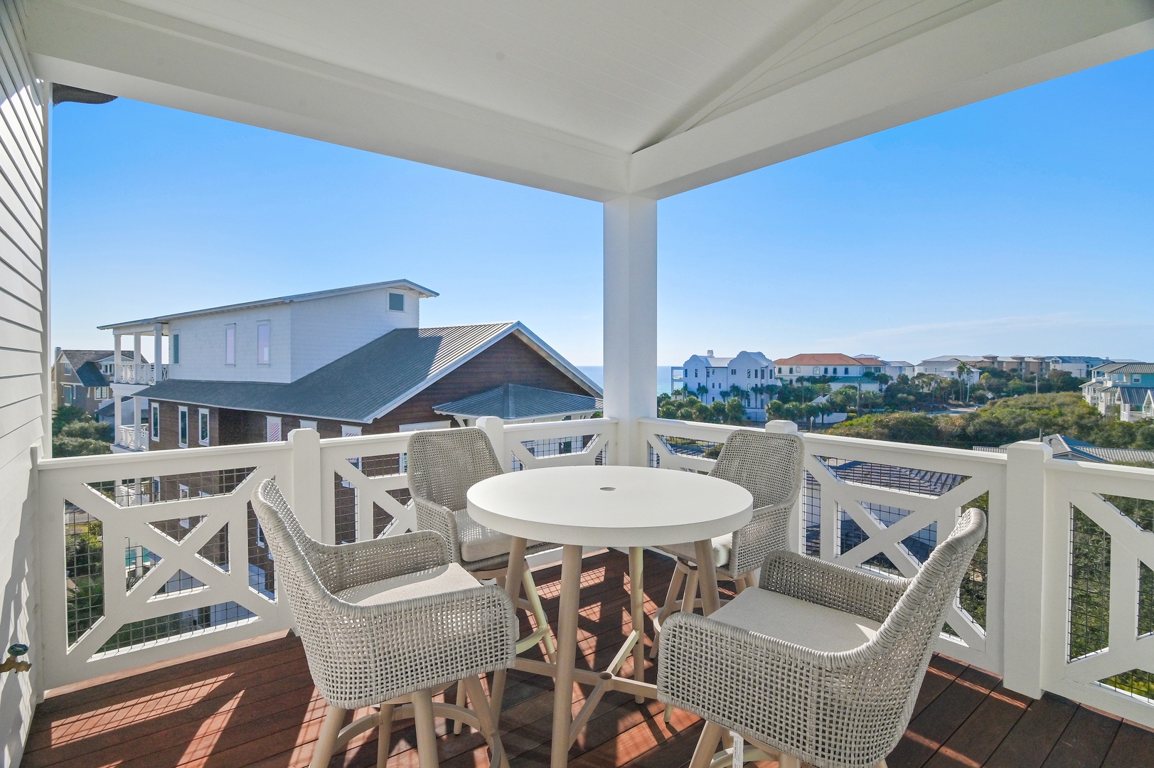 The elevated balcony offers neighborhood views and a comfortable outdoor dining setup, part of the property's coastal setting.