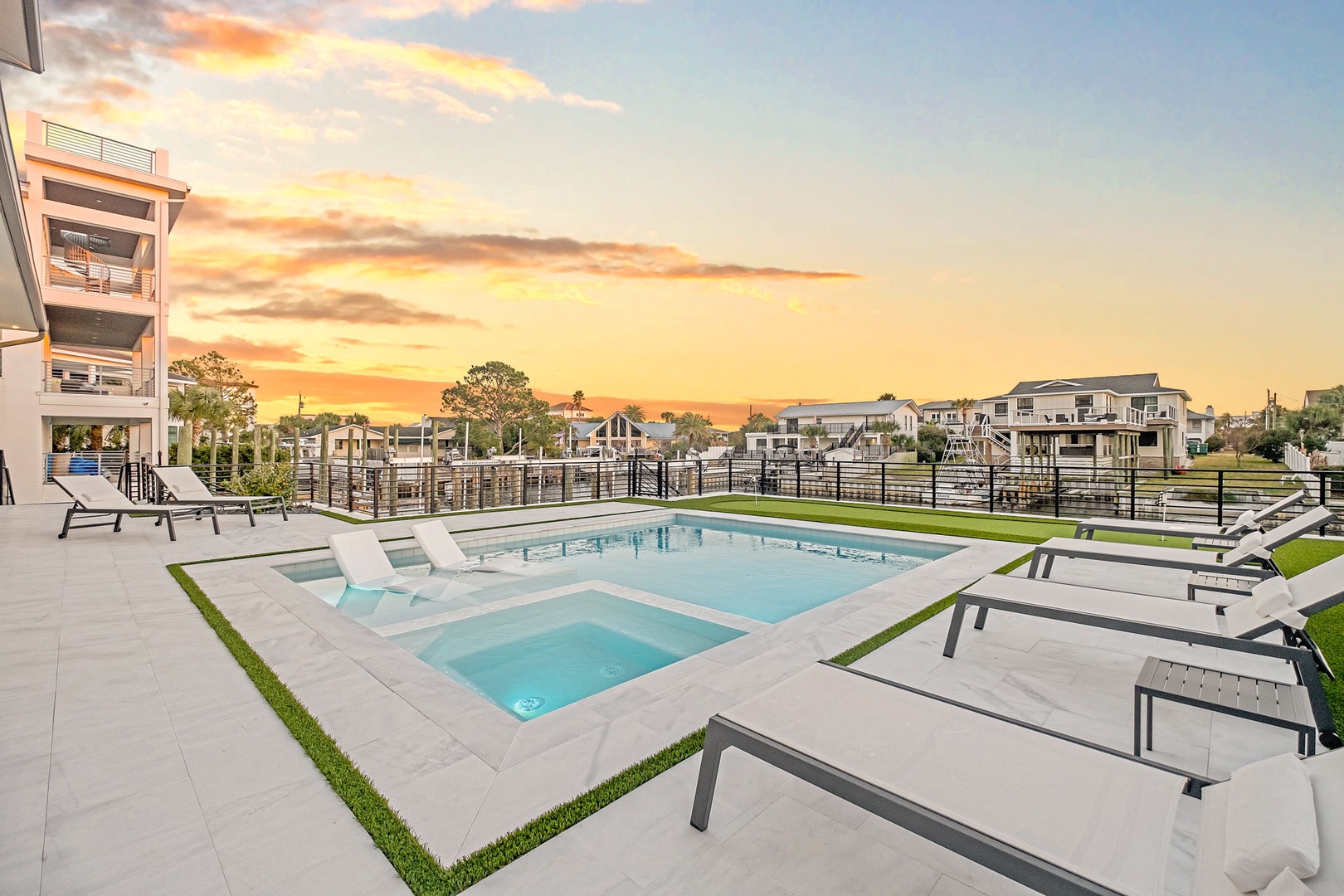 Modern pool and spa area with luxury loungers overlooking peaceful residential neighborhood at golden hour.