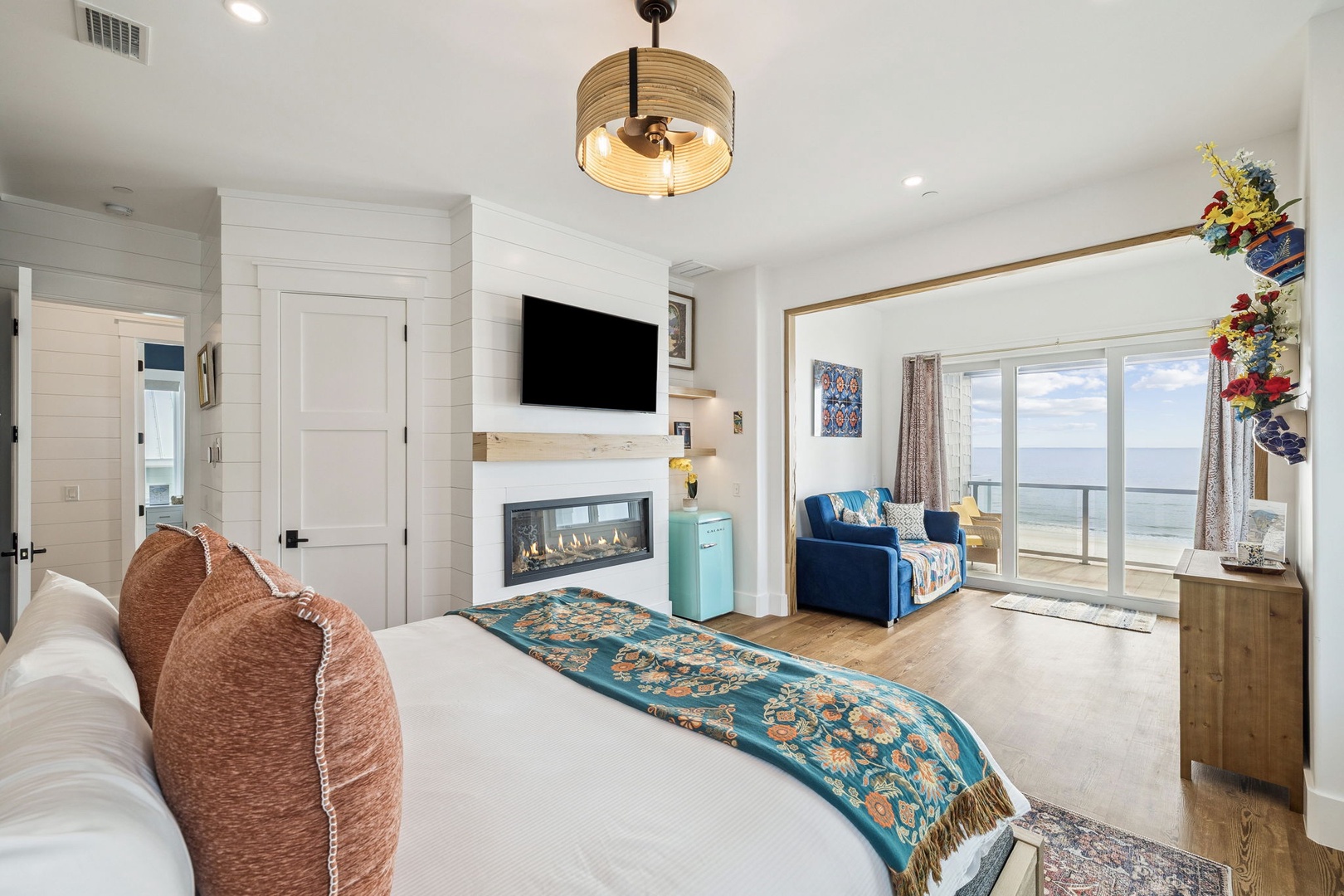 Unwind in your elegant bedroom with fireplace warmth, stunning ocean views through floor-to-ceiling windows, and coastal decor.