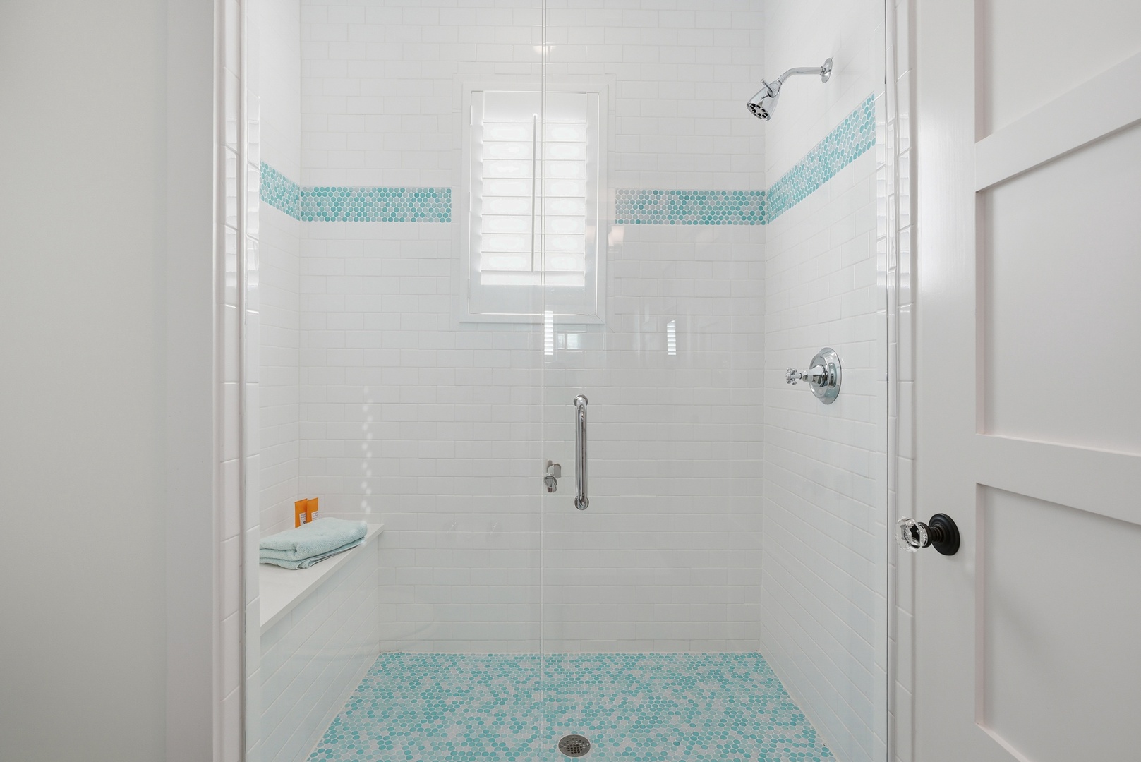 Step into your spa-like shower with crisp white subway tile, cheerful turquoise mosaic accents, and a built-in shelf for your essentials—a refreshing retreat after a day of adventure.