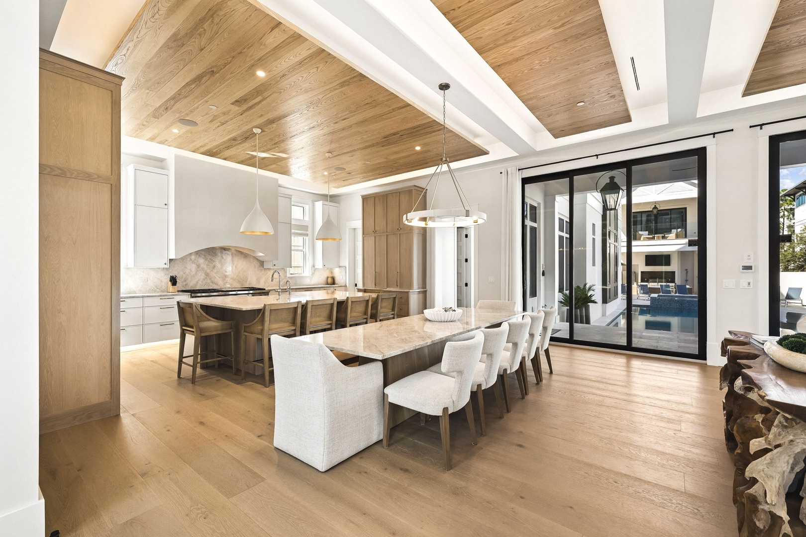 Picture yourself gathering around this stunning table, where warm wood tones meet elegant white accents. The soaring ceiling and abundant natural light create an inviting space perfect for unforgettable meals and conversations.