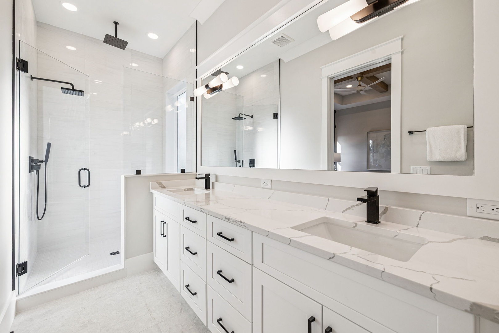 Step into your spa-like sanctuary with dual vanities, marble countertops, and a luxurious glass-enclosed shower with elegant rainfall features.