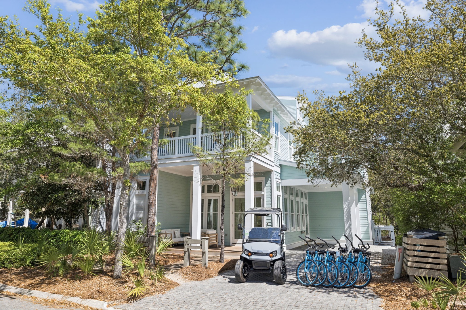 Charming coastal retreat with golf cart and bikes ready for exploring the tree-lined neighborhood.