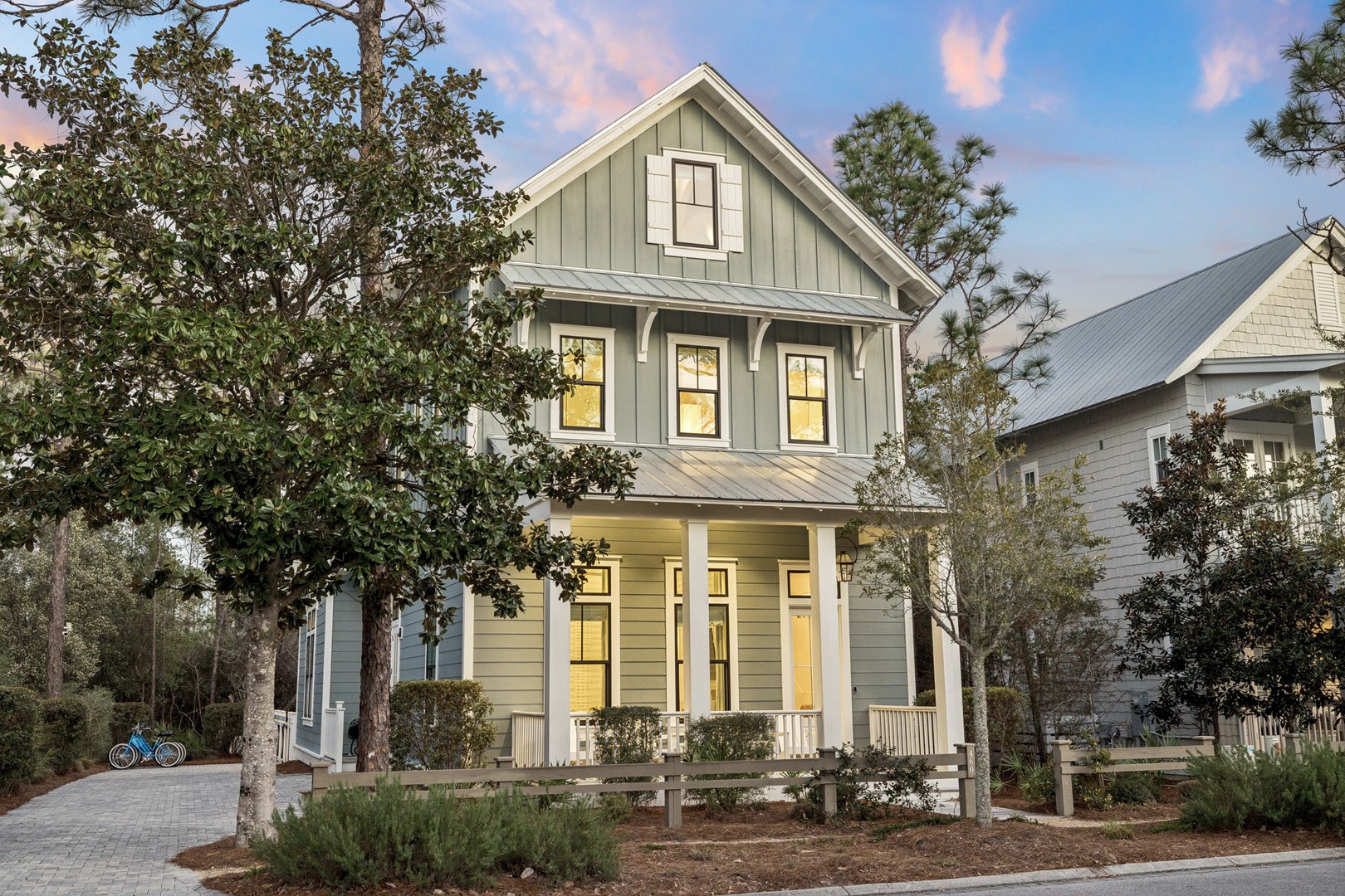 Charming two-story cottage with inviting front porch and modern coastal design in a peaceful residential neighborhood.