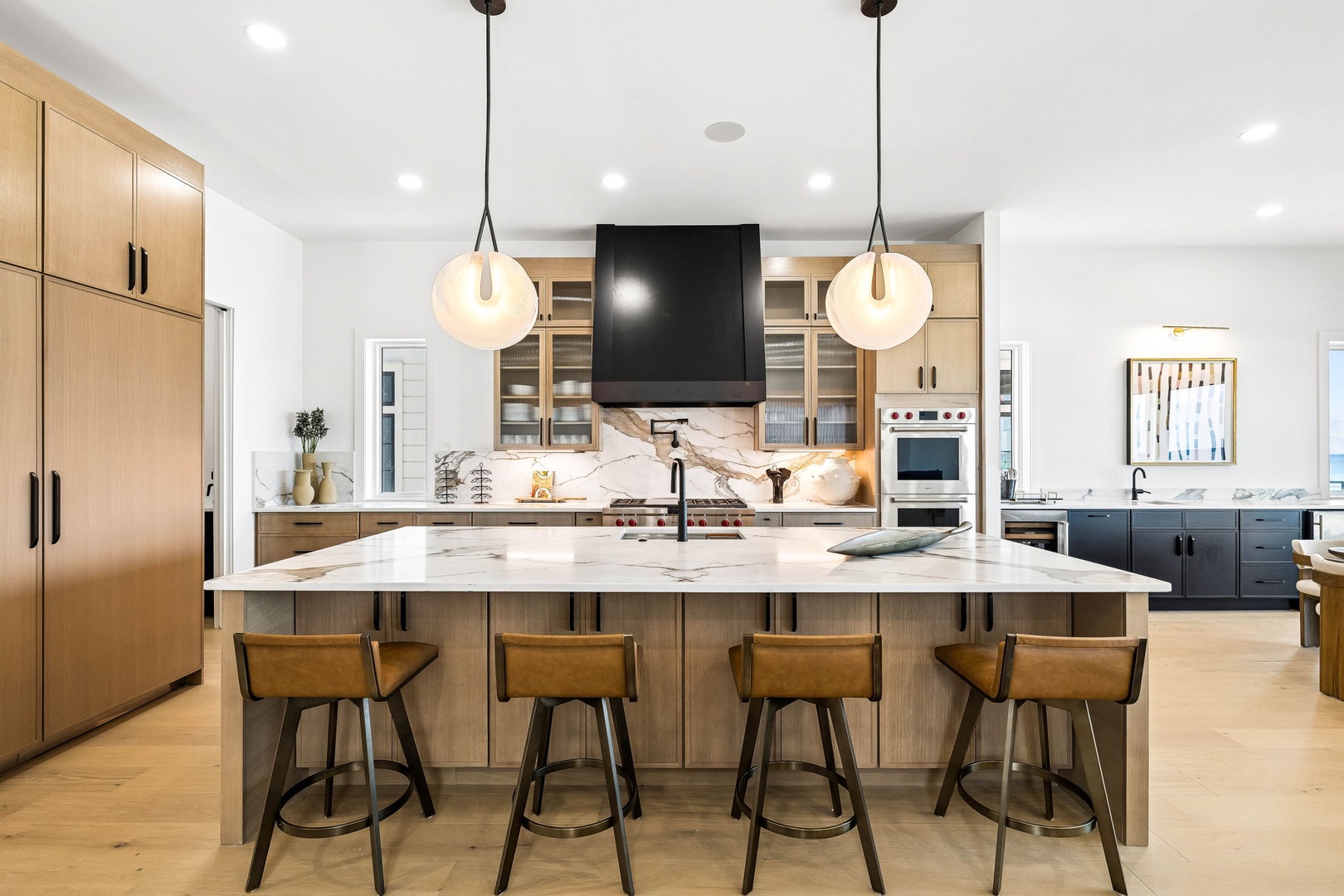 Step into this stunning chef's kitchen with its spacious marble island, modern appliances, and warm wood cabinetry—your perfect space for creating memorable meals together.