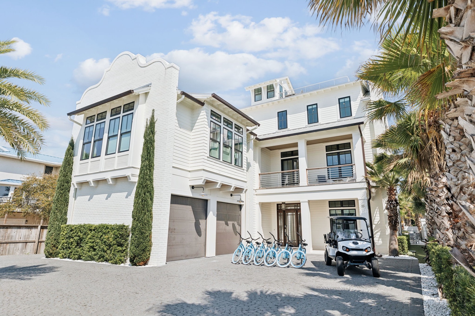 Modern coastal home with convenient bike rentals and golf cart for exploring the area, framed by tropical palms.