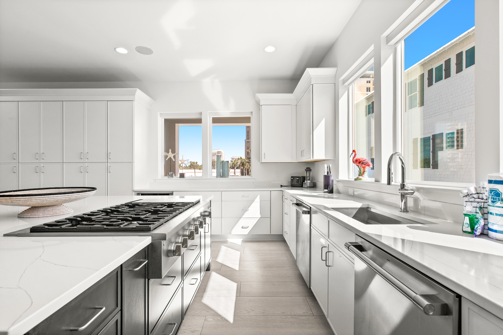 Step into this bright, modern kitchen where sleek white cabinetry and gleaming countertops invite you to cook and gather. City views frame your culinary adventures through sun-filled windows.