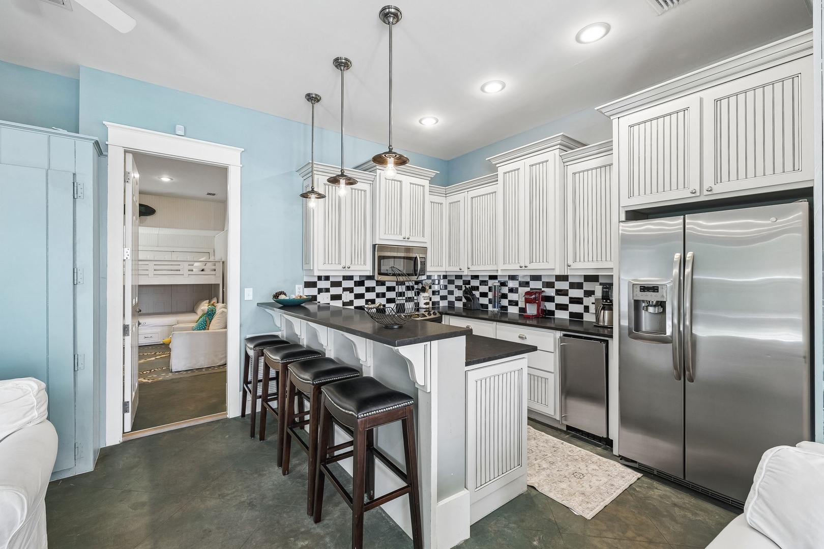 Your bright, fully equipped kitchen awaits with modern appliances, elegant white cabinetry, and a center island perfect for casual dining or meal prep.