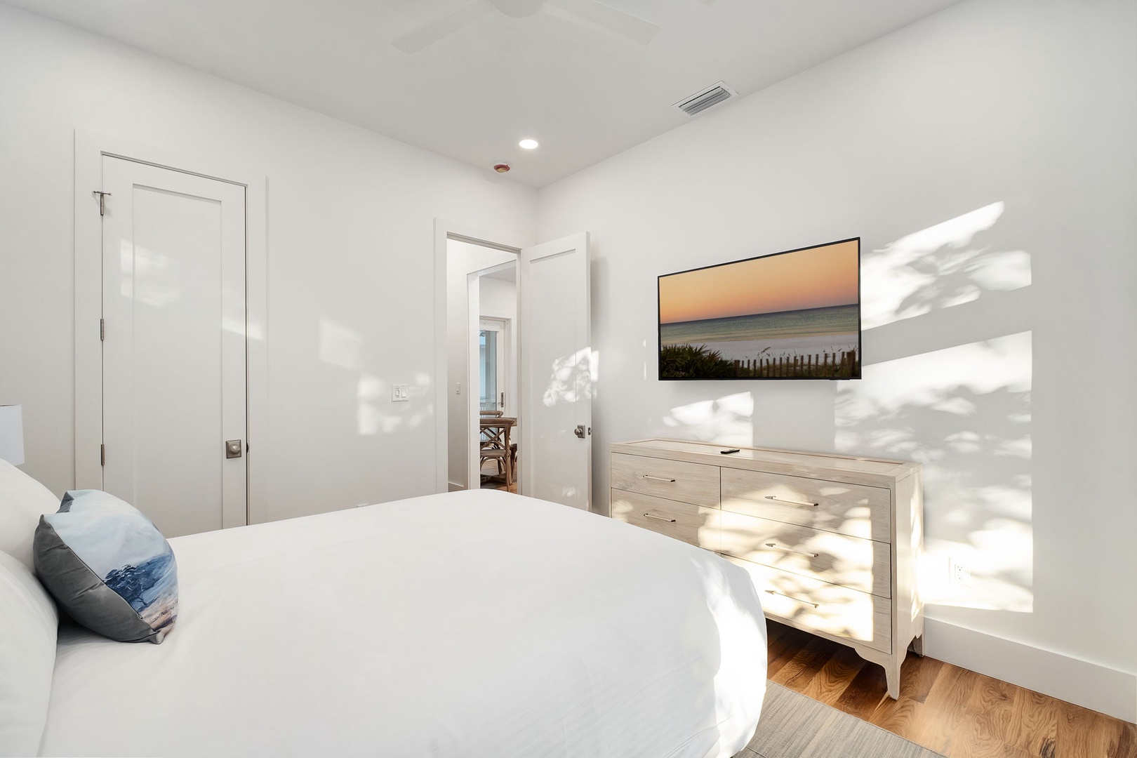 Sunlight dances across your serene bedroom, creating peaceful shadows on crisp white linens and warm wood floors for restful nights.