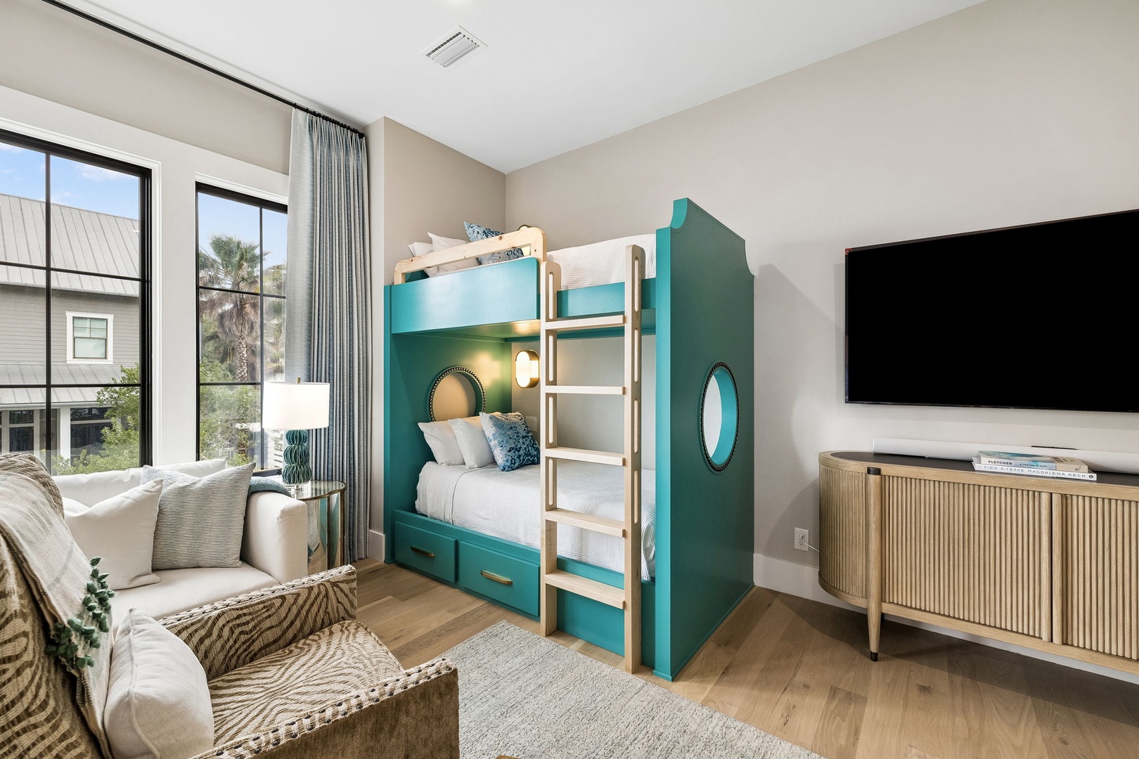 Unwind in your bright bedroom with custom bunk beds, a cozy sofa, and entertainment at your fingertips—ideal for family fun.