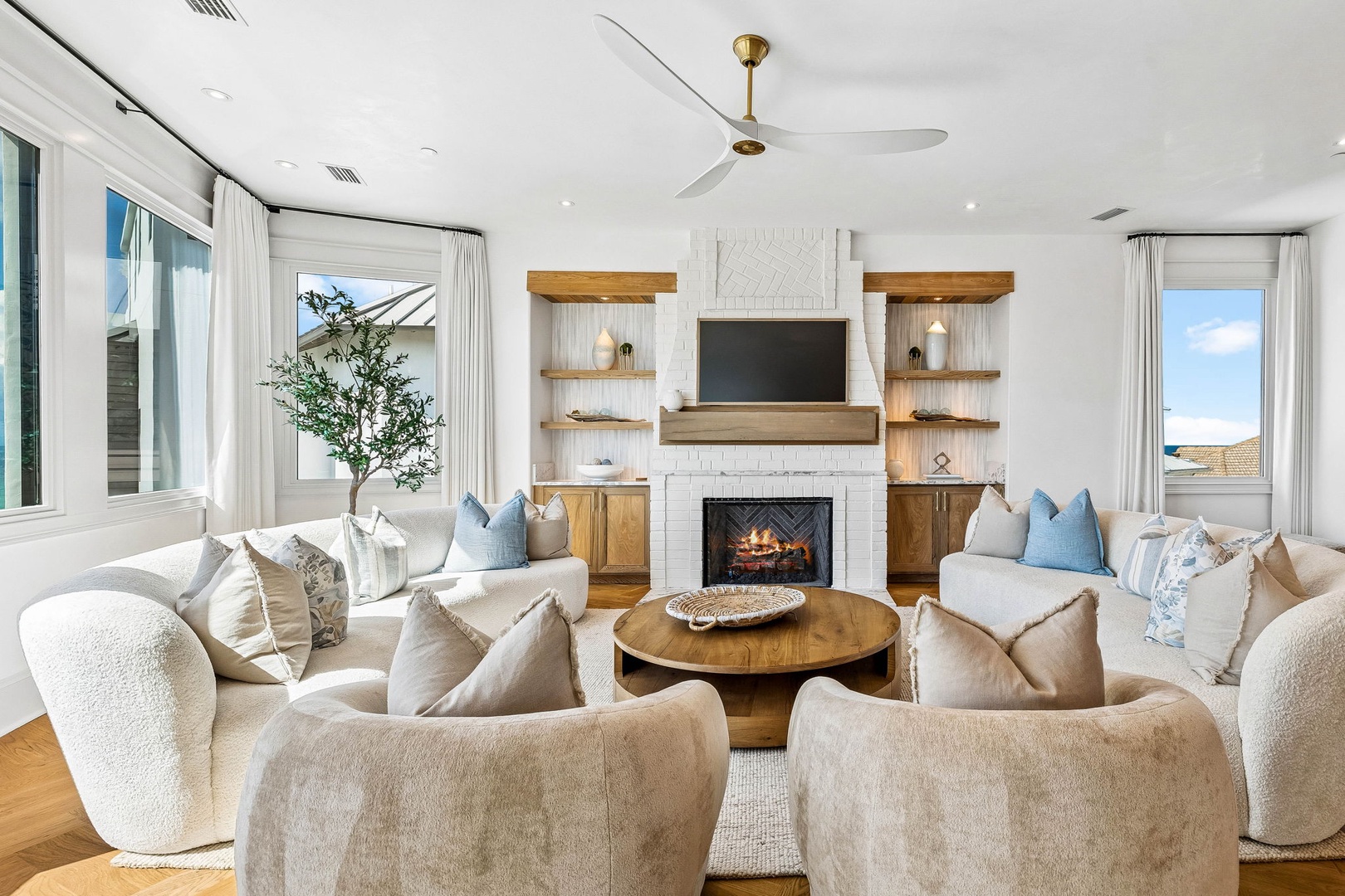 Sink into plush seating arranged around a warm fireplace, where soft textures and natural light create your perfect space to unwind together.
