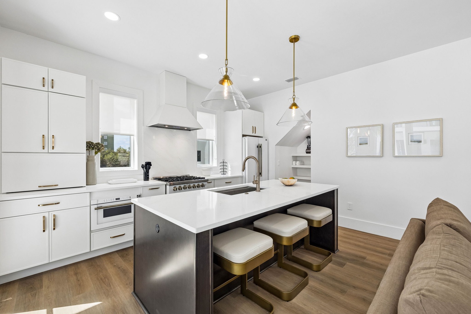 Prepare your favorite meals in this sleek, sunlit kitchen outfitted with high-end appliances, a spacious island, and stylish pendant lights—perfect for gathering and creating culinary memories.