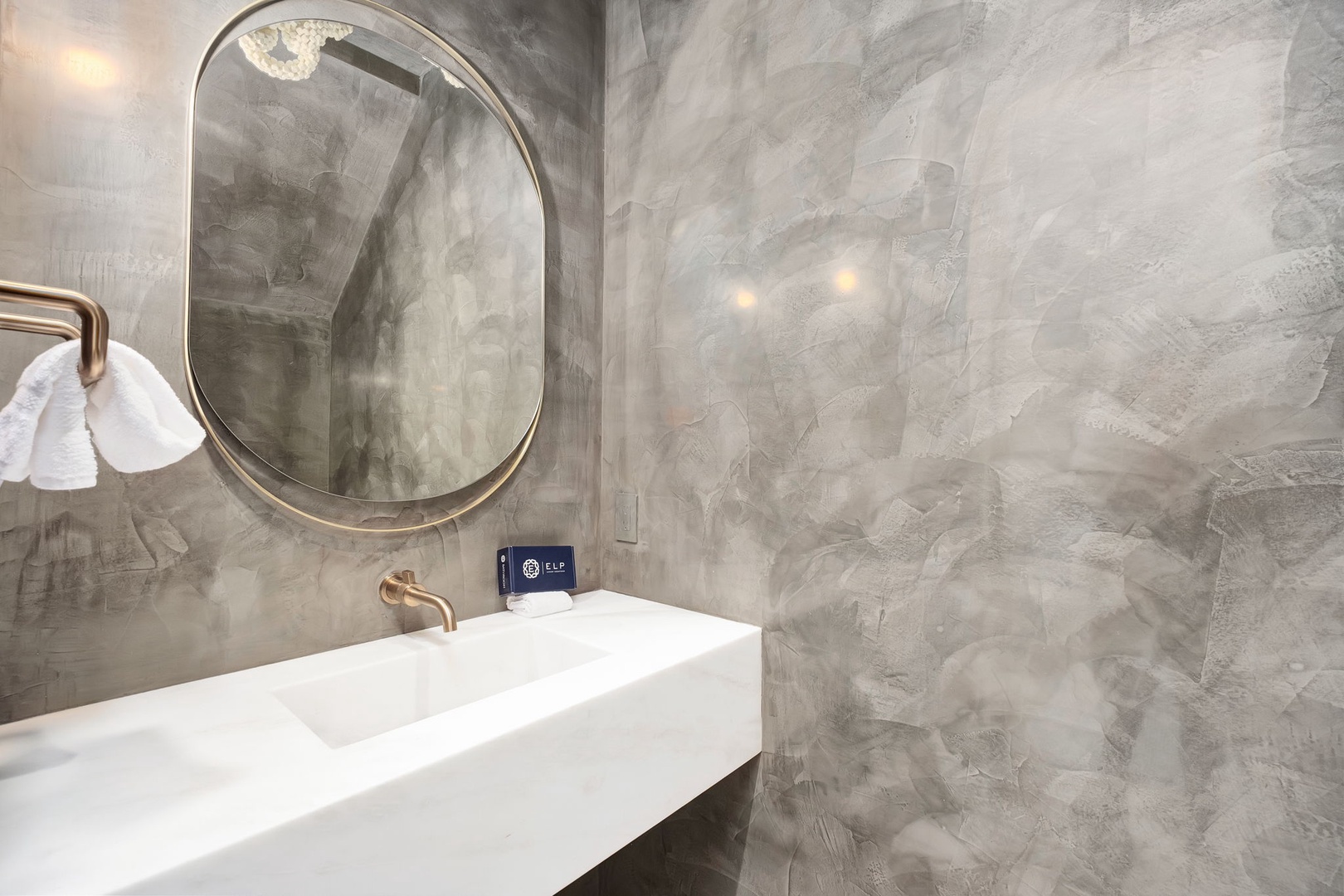 Step into your private spa-like bathroom, where artistic concrete walls and a sculptural mirror frame your crisp white vanity. Every detail invites you to unwind in modern luxury.
