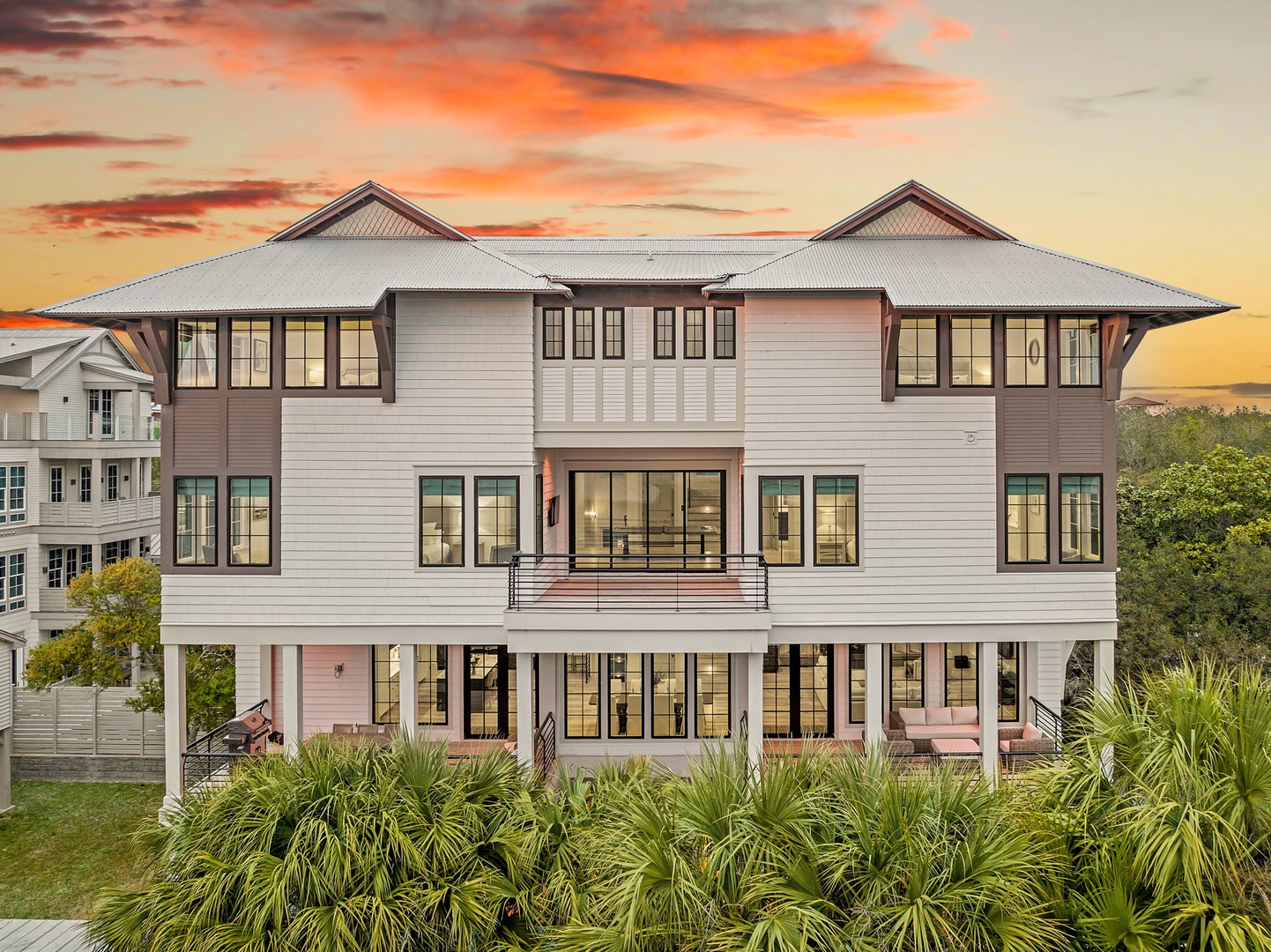 Stunning coastal property featuring elevated architecture with wraparound porches beneath a breathtaking sunset sky.