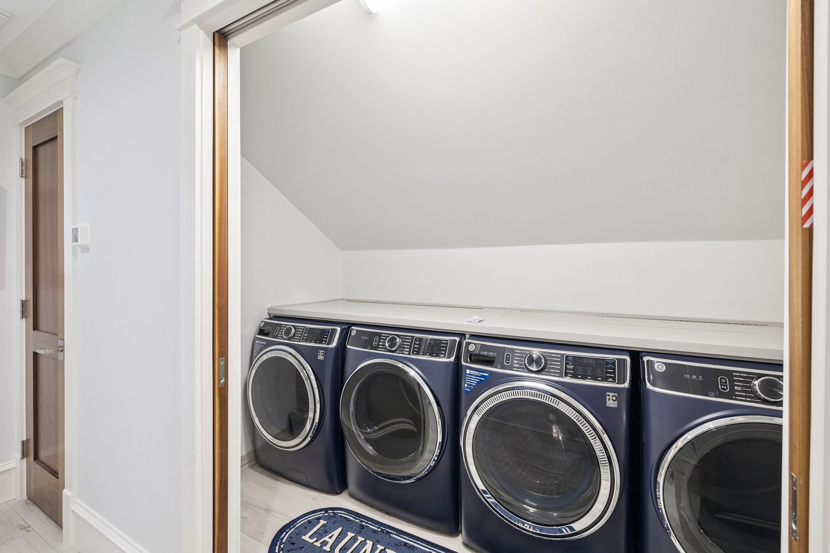 Your laundry stays organized with multiple washers and dryers tucked neatly under the sloped ceiling.