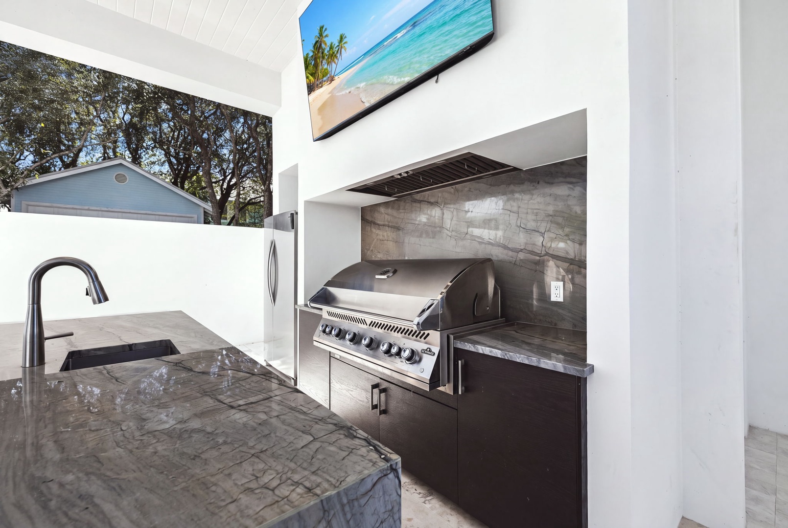 Your private outdoor kitchen awaits, complete with a sleek built-in grill and concrete counters—perfect for alfresco dining under the open sky.