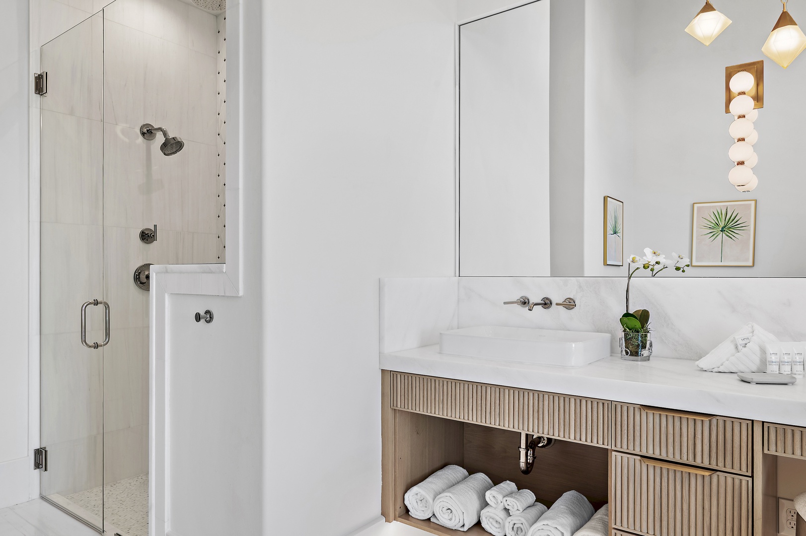 Step into your spa-like bathroom where bright coastal details meet calming marble tones. Refresh under the rain shower, then pamper yourself at the elegant vanity surrounded by lush greenery.