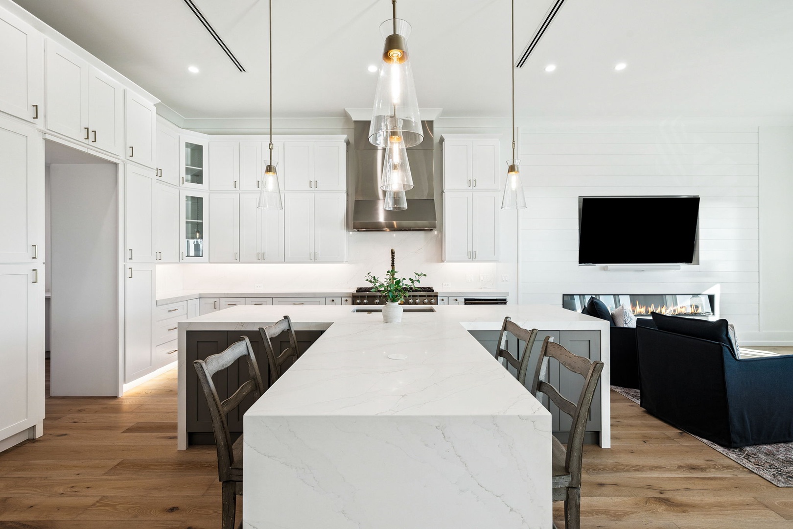 Your gourmet kitchen awaits with sleek white cabinetry, marble island, and pendant lighting creating the perfect space for memorable meals together.