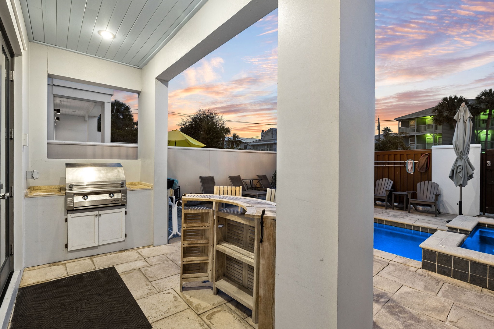 Soak in stunning sunset hues from your private patio, where a built-in grill and poolside seating invite effortless outdoor entertaining and relaxation.