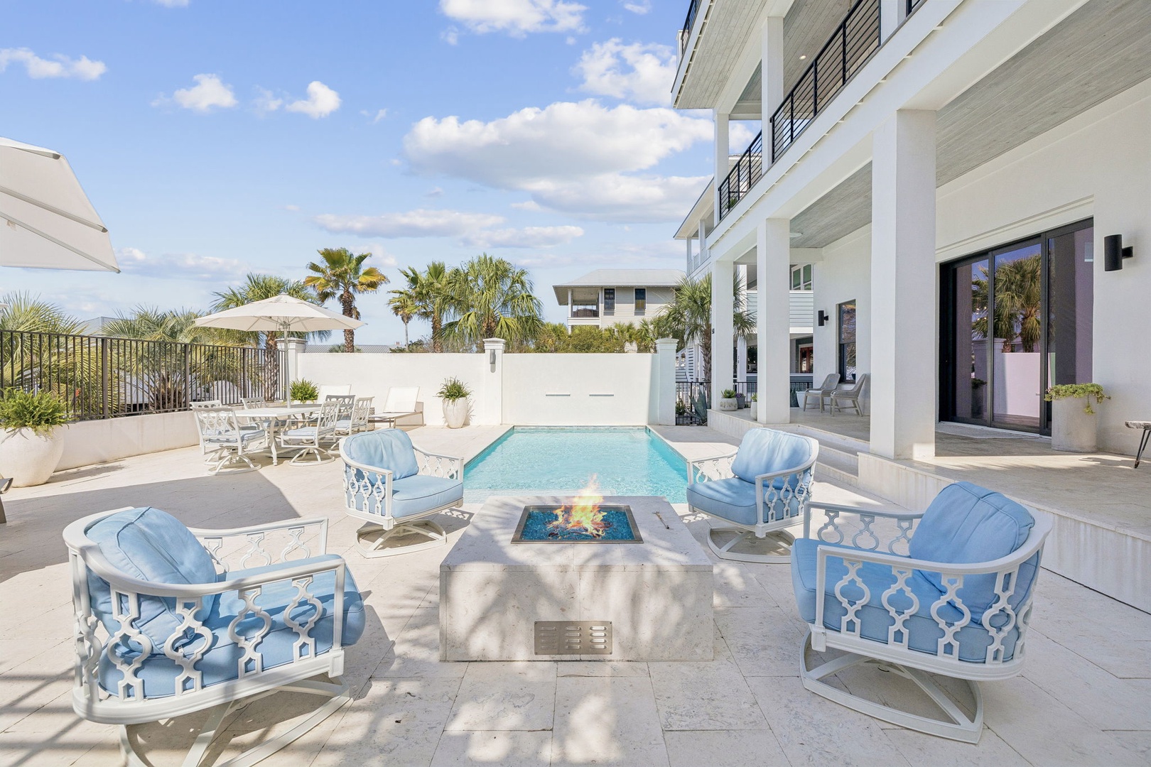 Unwind in your private poolside paradise with plush blue seating and a cozy fire pit for evening gatherings.