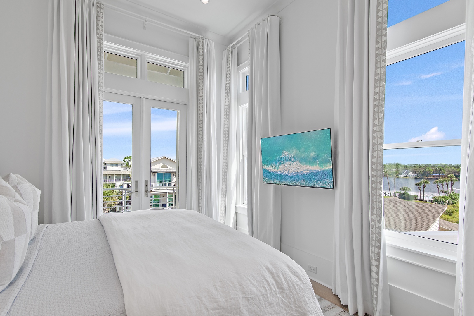 Wake up to peaceful water views and natural light streaming through tall windows in your serene bedroom retreat. The bright, airy space invites you to start each day surrounded by coastal beauty.