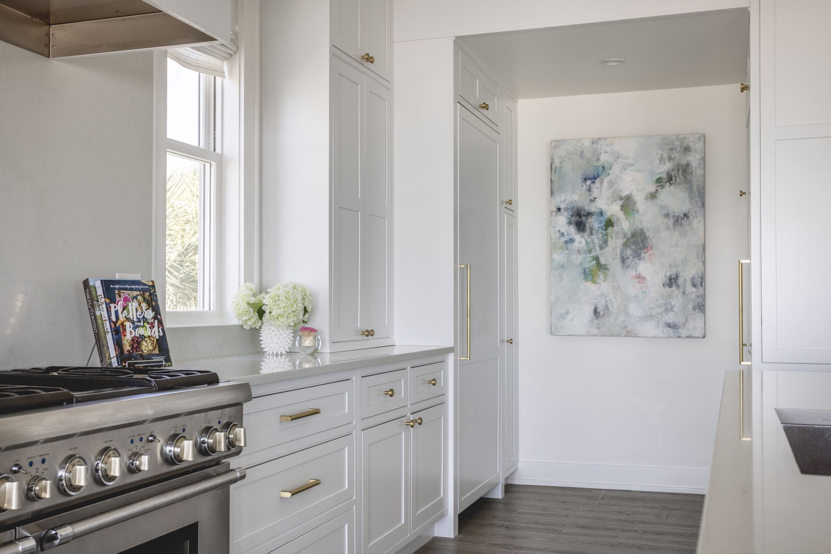 Step into this bright, elegant kitchen where clean lines and classic design meet modern convenience. Natural light pours in, highlighting the custom cabinetry and professional-grade range that's ready for your culinary adventures.