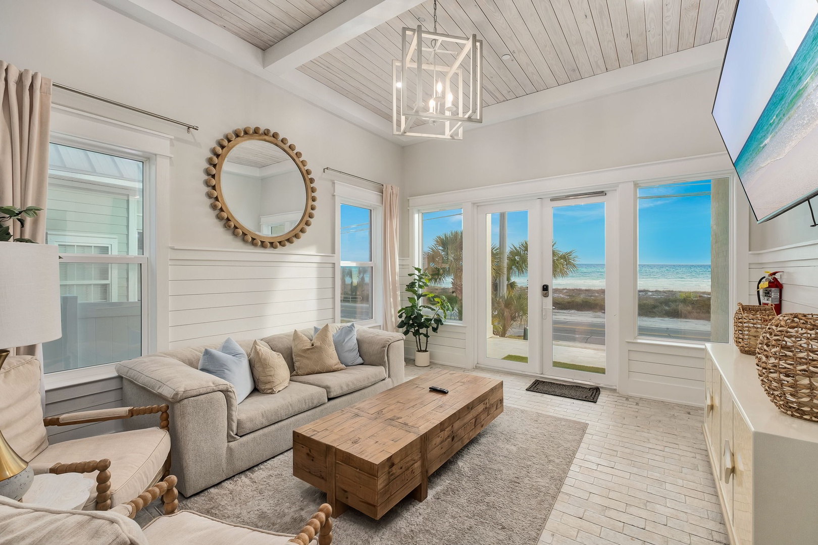 Relax in your bright coastal living room where ocean views meet modern comfort through expansive glass doors.