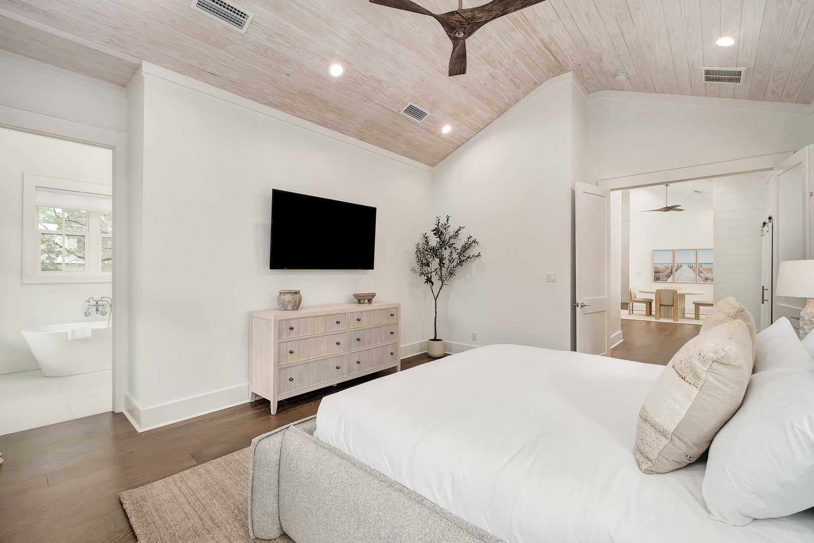 Sink into plush bedding beneath soaring wood-beamed ceilings while your favorite shows play on the wall-mounted TV in this serene coastal retreat.