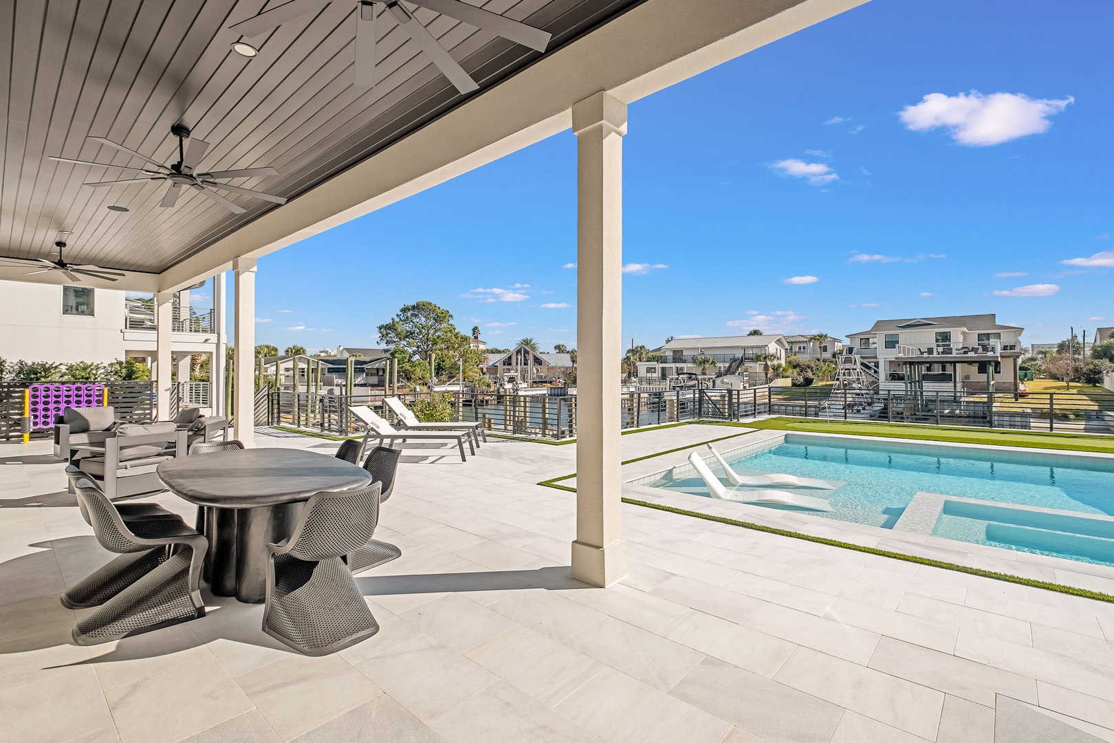 Step onto your covered terrace where poolside dining awaits under elegant ceiling fans, framing stunning waterfront views.