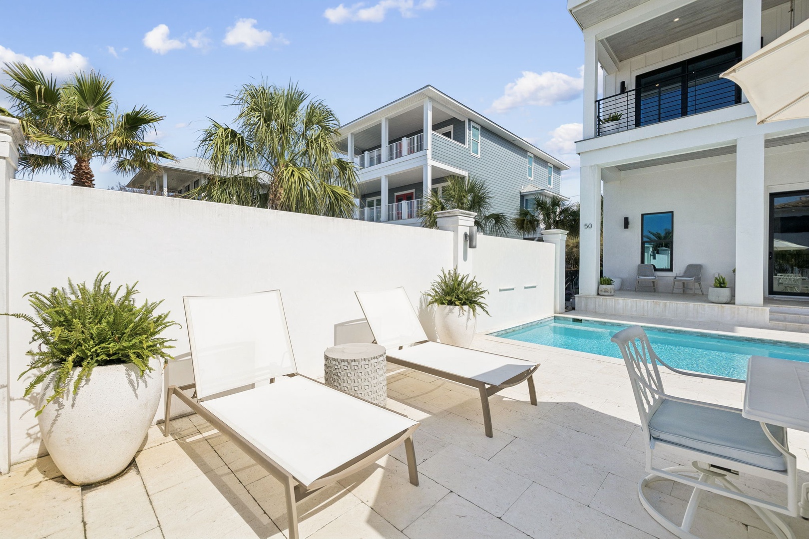 Your private poolside retreat awaits with plush lounge chairs and tropical palms creating the perfect sunny sanctuary.
