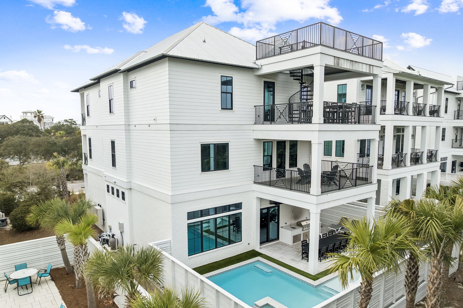 Modern coastal home with private pool, multiple balconies, and rooftop deck surrounded by lush tropical landscaping.