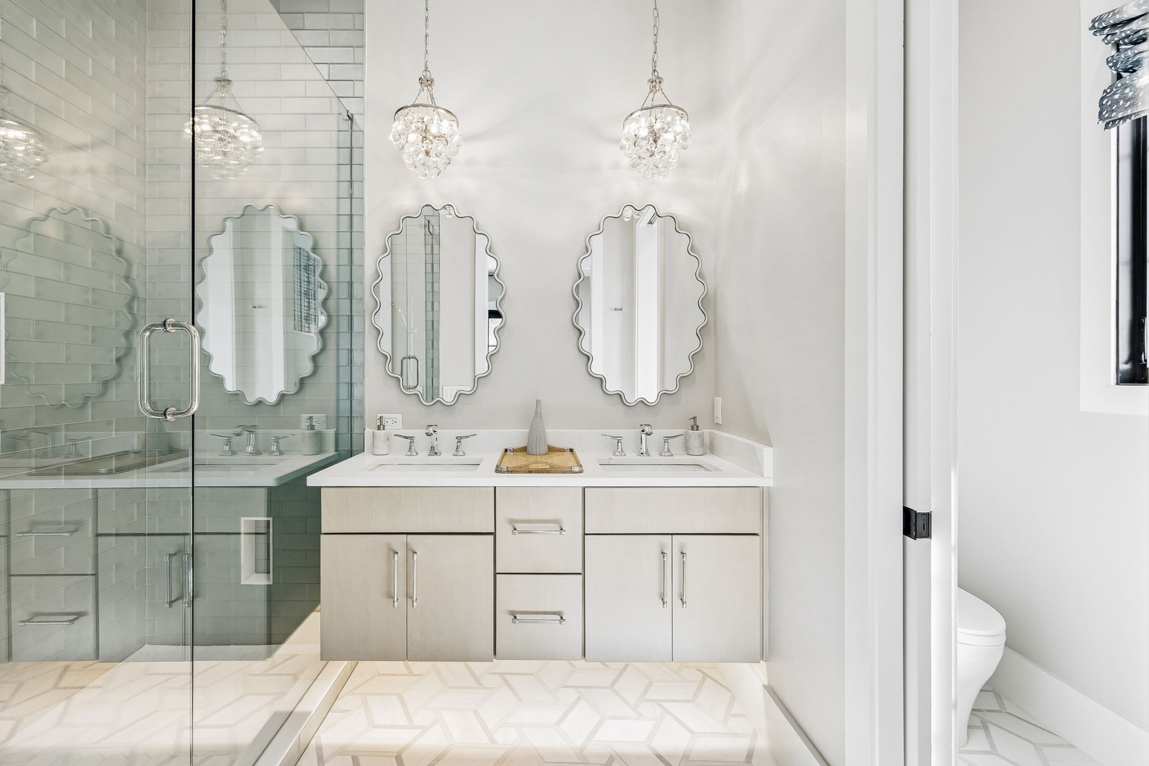 Luxurious dual vanities with elegant mirrors invite you to start your day in style, while the spa-like shower and sparkling chandeliers create a serene retreat.