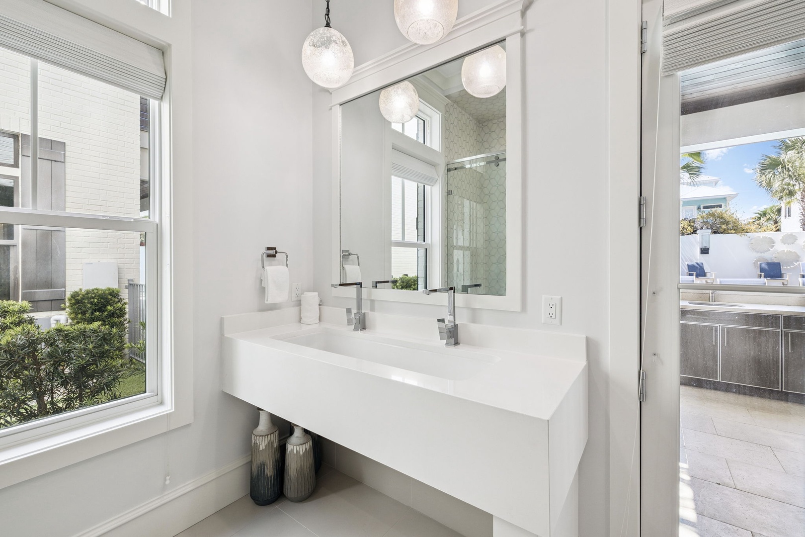 Refresh in your sleek bathroom with dual sinks, elegant pendant lighting, and bright natural light streaming through large windows.